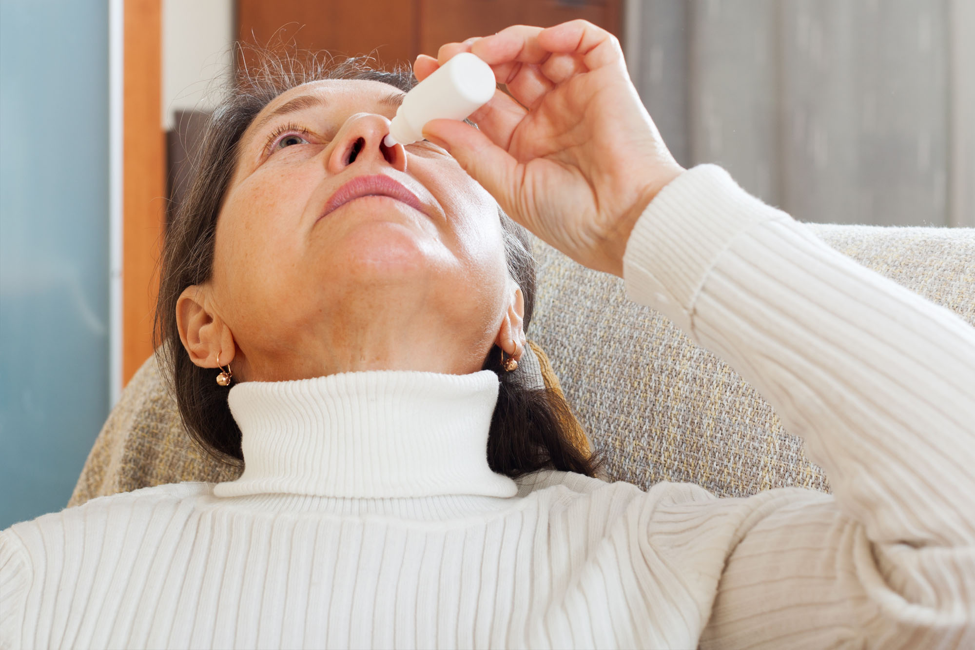 woman using nasal drops, or nasya, in her nose