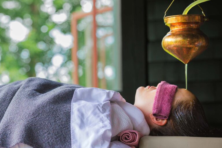 woman with warm oil being poured on her head during a panchakarma treatment