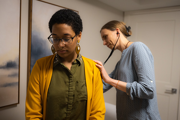 Ayurvedic student performing an Ayurvedic consultation with a patient, and listens to her heartbeat with a stethoscope